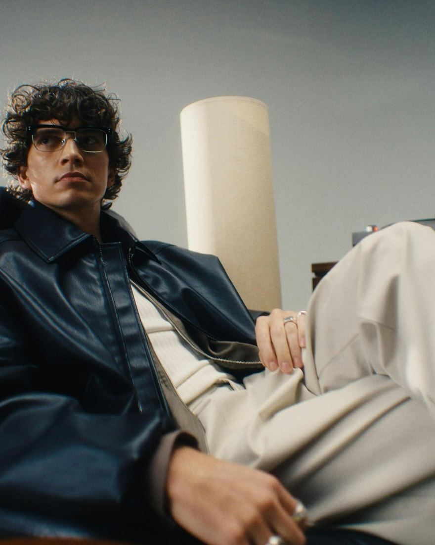 Man in glasses seated in a leather jacket